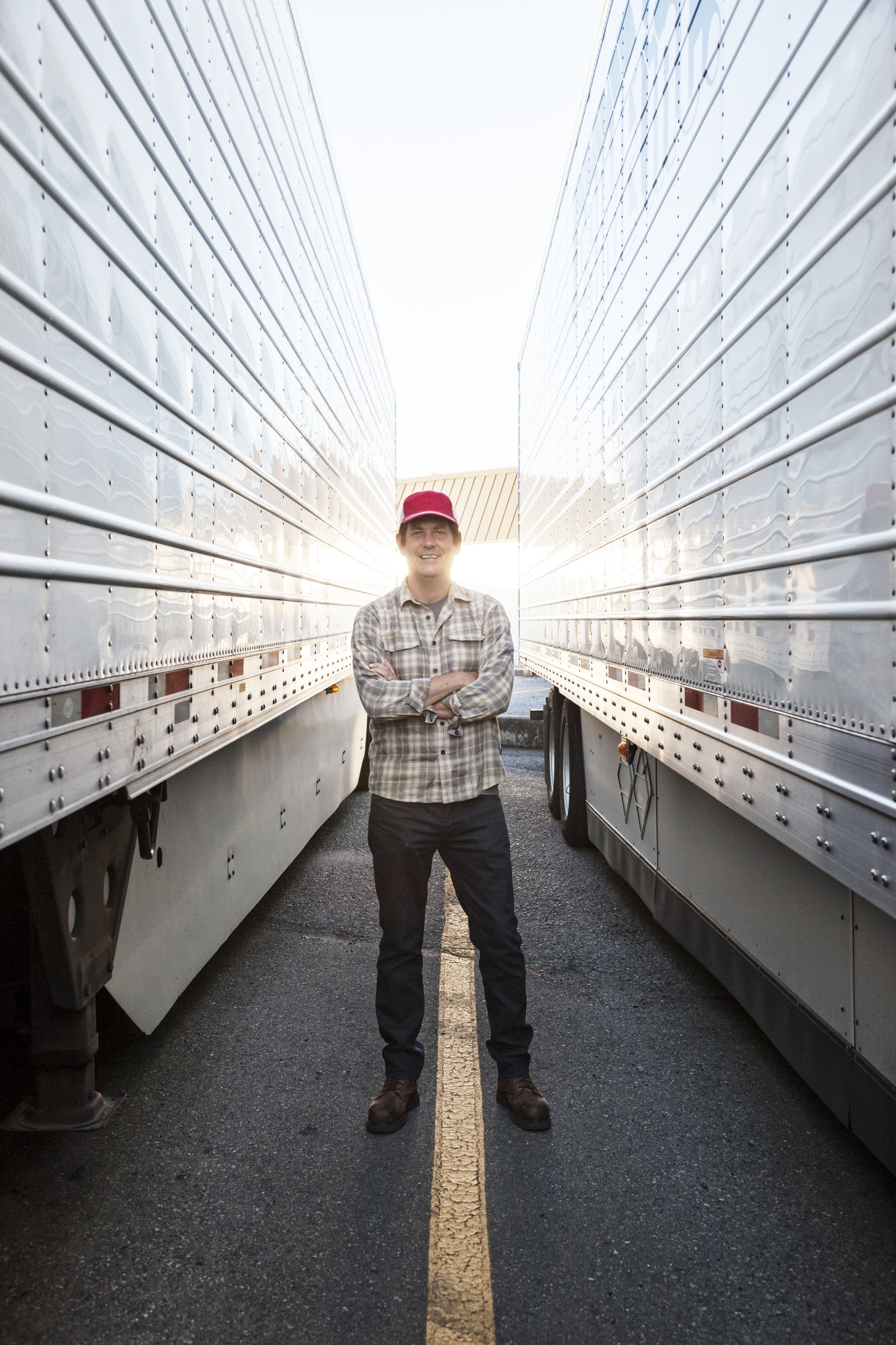 Caucasian man truck driver with his truck parked in a lot at a truck stop.